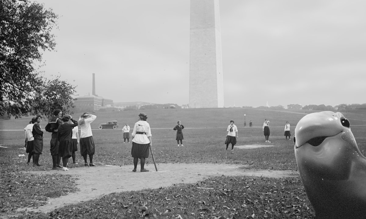 Women are playing baseball in front of the Washington Monument, 1919 -- and Murf pokes his head into the shot