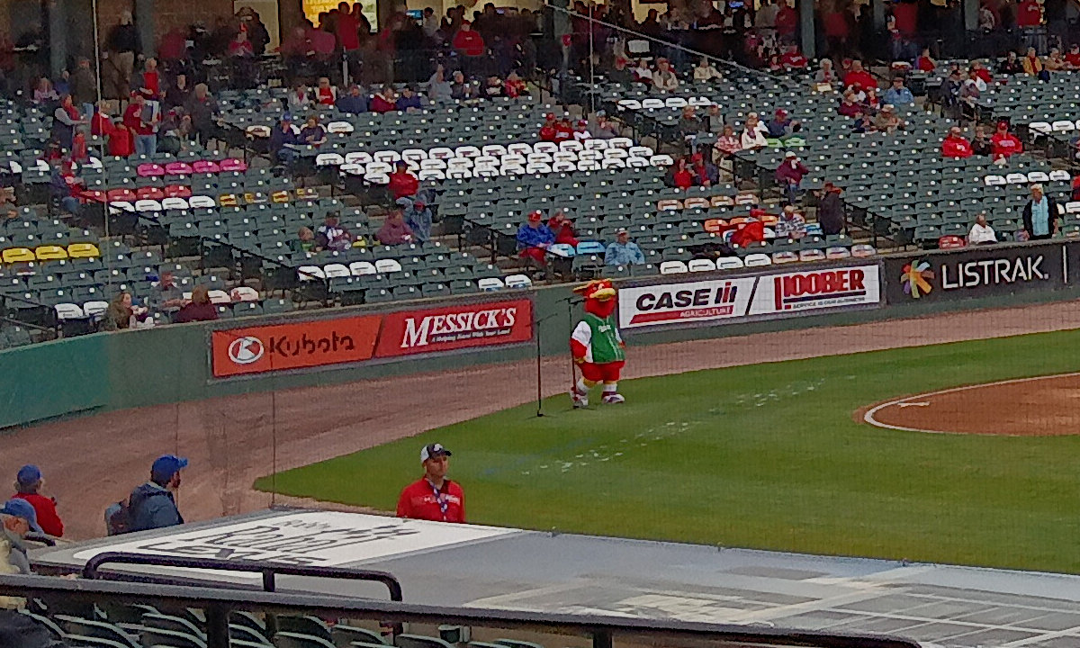 Cylo, the mascot, looks a bit alone and sad on the field grass behind home plate.