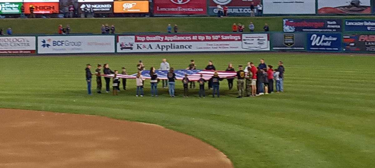 The Junior Marines, holding an American flag on the outfield of Clipper Magazine Stadium before the Star-Spangled Banner.