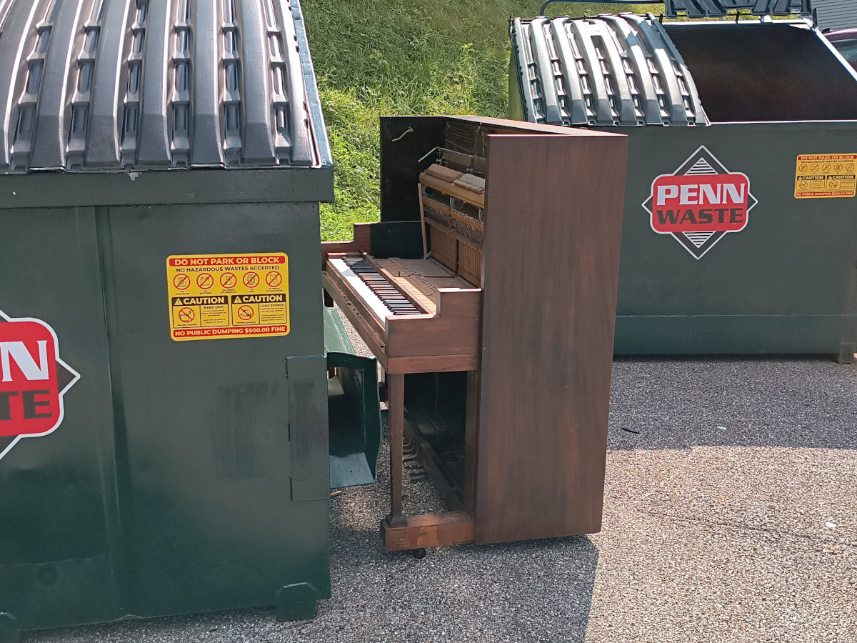 A piano, abandoned next to the dumpsters in my apartment complex's parking lot
