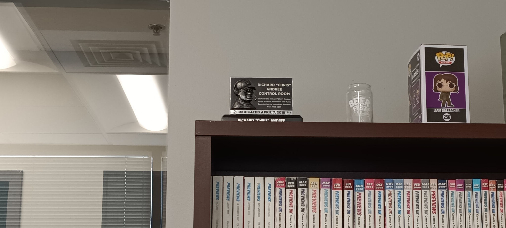 Chris Andree plaque sitting atop my bookshelf of PREVIEWS, next to a Liam Gallagher Funko POP!