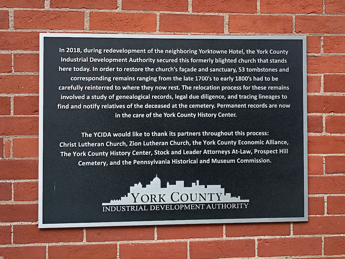 Sign placed by the York County Industrial Development Authority explaining how in 2018 work on the Yorktowne Hotel necessitated moving and reinterring the graves located here.