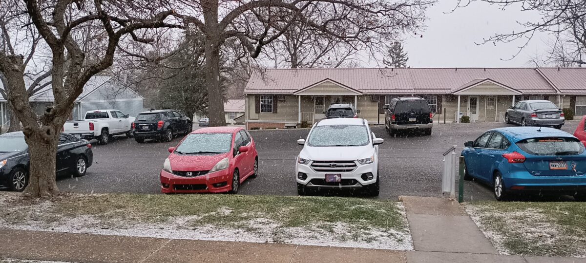 Snow falling on the cars in the parking lot outside of my apartment