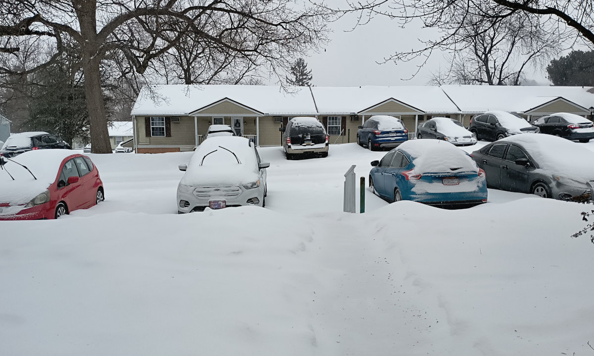 The view outside, a little bit past Noon. The sidewalk has been covered with snow and ice.