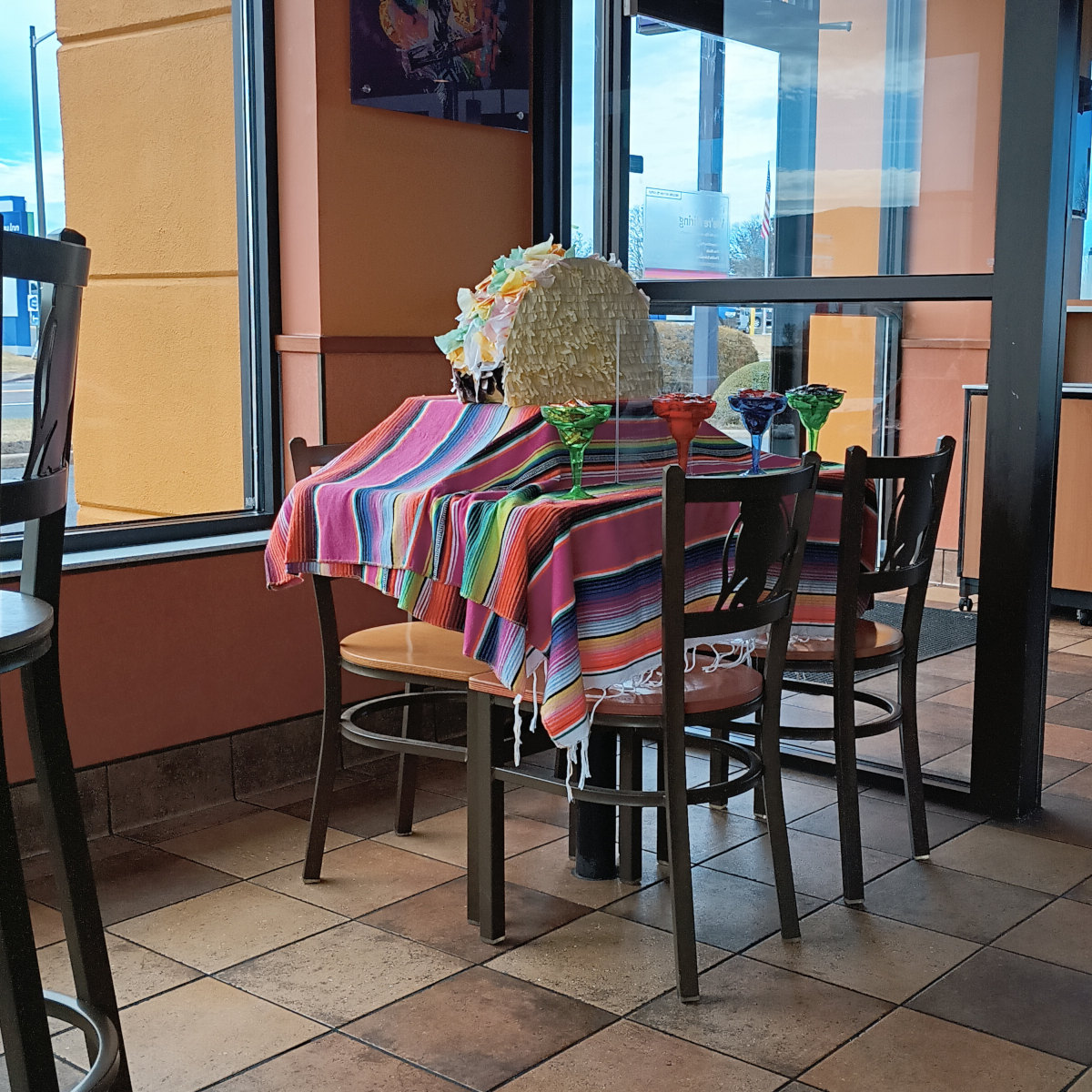 The Missing Taco table at Taco Bell, with a tablecloth, plastic margarita glasses, and giant tacos