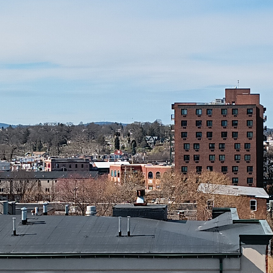 The facade of WellSpan Park, as seen from the top of the parking garage, and beyond it a hillside of grave markers